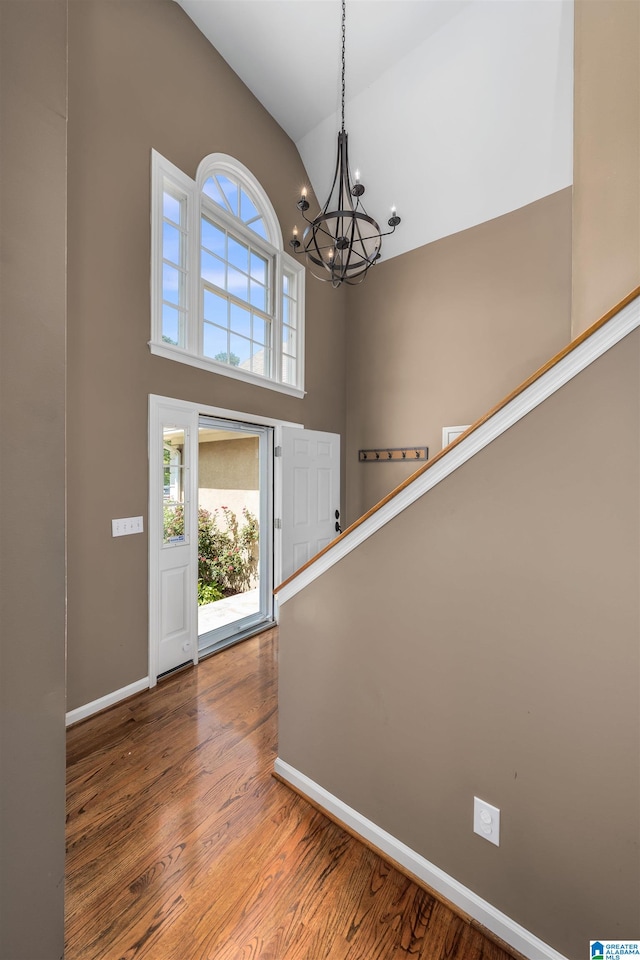 foyer featuring a towering ceiling, an inviting chandelier, and hardwood / wood-style floors