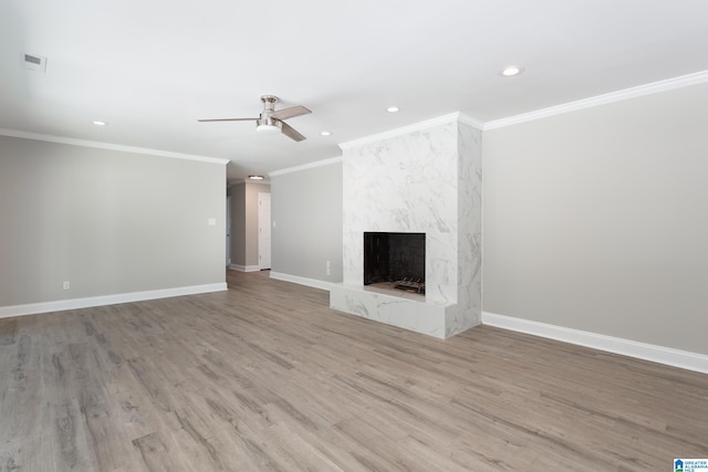 unfurnished living room featuring ceiling fan, light wood-type flooring, crown molding, and a fireplace