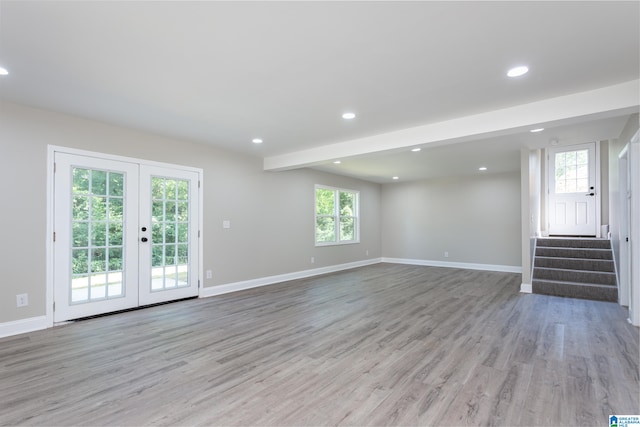 unfurnished living room with a wealth of natural light, french doors, and light hardwood / wood-style floors