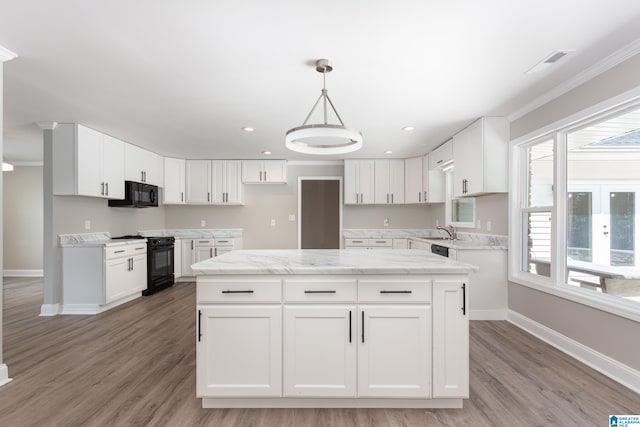 kitchen featuring light hardwood / wood-style flooring, white cabinets, a center island, and black appliances