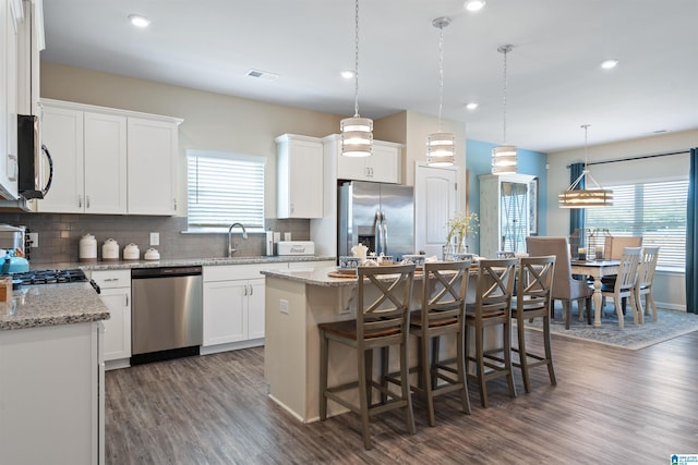 kitchen with dark hardwood / wood-style flooring, tasteful backsplash, appliances with stainless steel finishes, and a kitchen island