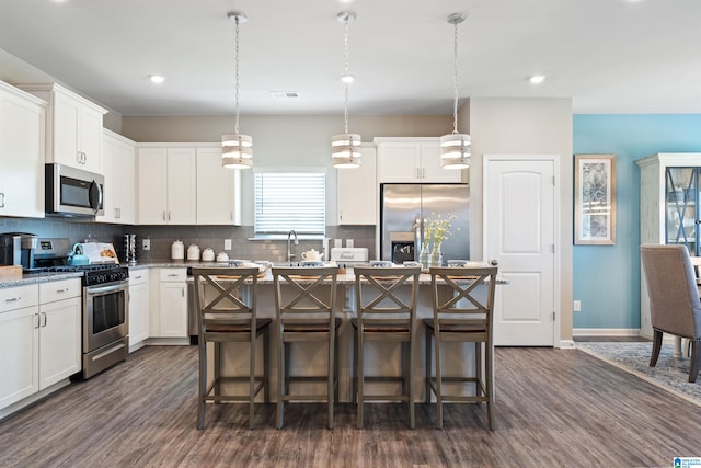 kitchen with dark hardwood / wood-style flooring, white cabinets, appliances with stainless steel finishes, and a kitchen island