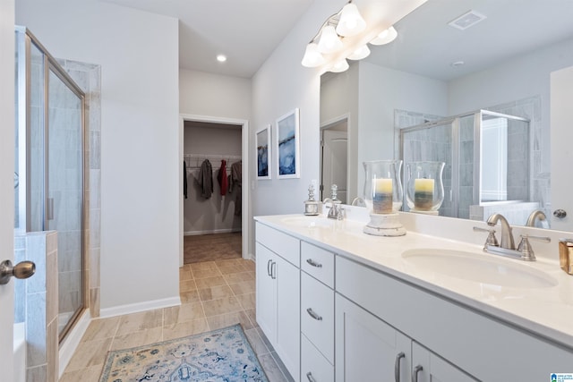 bathroom with a shower with door, vanity, and tile patterned floors