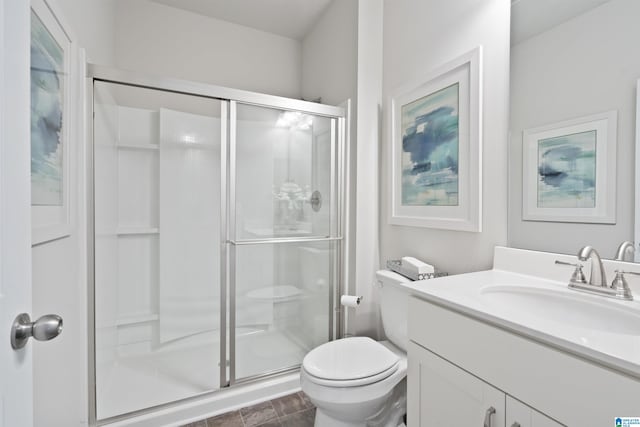 bathroom featuring a shower with door, toilet, and vanity