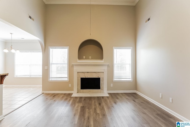 unfurnished living room with hardwood / wood-style flooring, a high end fireplace, and a healthy amount of sunlight