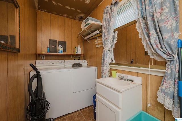 laundry room featuring sink, washer and clothes dryer, wooden walls, and dark tile patterned floors