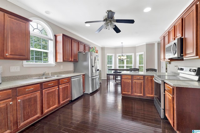 kitchen with a sink, light countertops, appliances with stainless steel finishes, dark wood finished floors, and decorative light fixtures