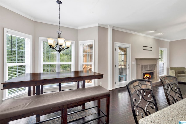 dining room with ornamental molding, a chandelier, dark wood finished floors, and a premium fireplace