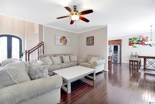 living area with arched walkways, ceiling fan with notable chandelier, stairway, dark wood finished floors, and crown molding