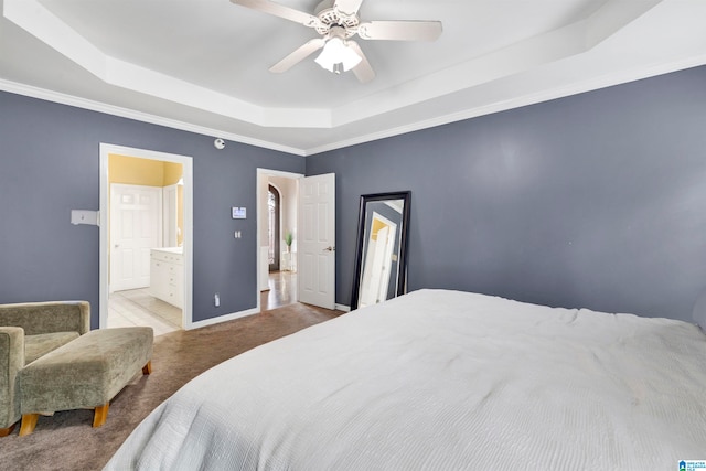 bedroom with light carpet, baseboards, ensuite bath, ceiling fan, and a tray ceiling