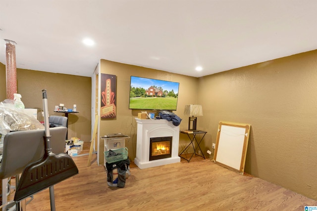 living room featuring light wood finished floors, a glass covered fireplace, and recessed lighting