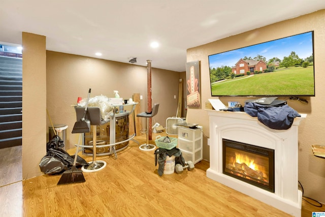 interior space with a glass covered fireplace, wood finished floors, and recessed lighting