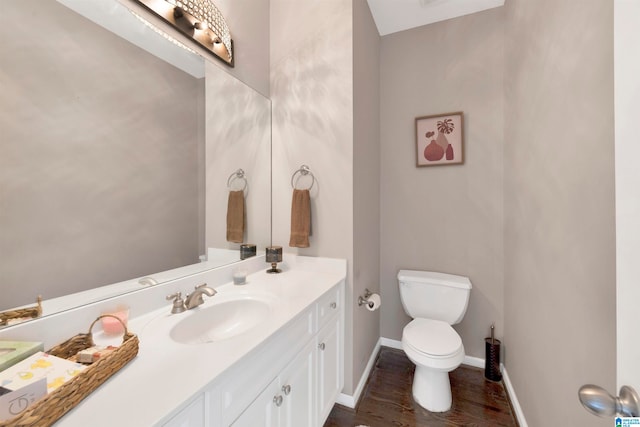 bathroom with toilet, vanity, baseboards, and wood finished floors