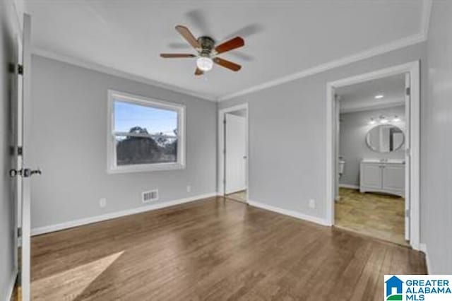 unfurnished bedroom with connected bathroom, dark wood-type flooring, visible vents, baseboards, and crown molding