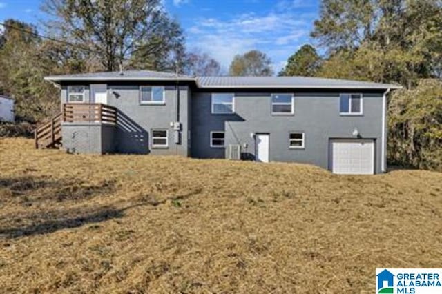 back of property with an attached garage, stairway, and a yard