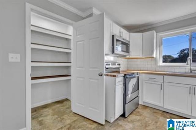 kitchen featuring crown molding, backsplash, appliances with stainless steel finishes, white cabinets, and a sink