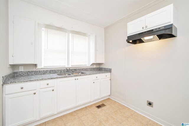 kitchen featuring sink, white cabinets, light stone counters, and light tile patterned flooring