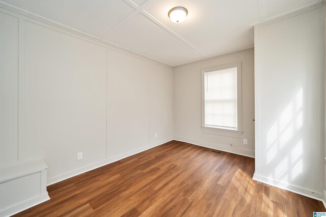 spare room with hardwood / wood-style flooring and crown molding