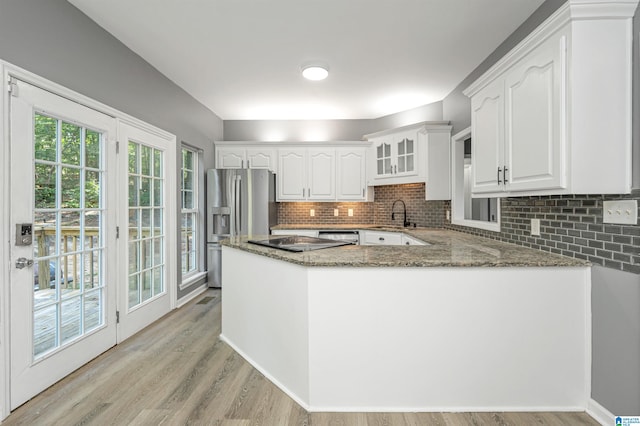 kitchen featuring sink, kitchen peninsula, light hardwood / wood-style flooring, and dark stone countertops