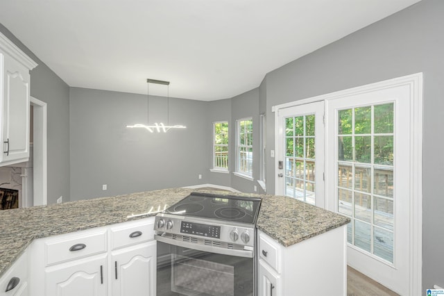 kitchen with electric range, plenty of natural light, and white cabinets