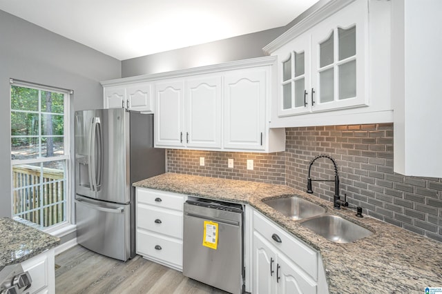 kitchen featuring white cabinets, glass insert cabinets, appliances with stainless steel finishes, a sink, and backsplash