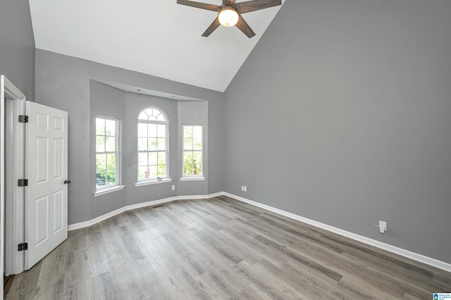 spare room featuring ceiling fan, high vaulted ceiling, wood finished floors, and baseboards