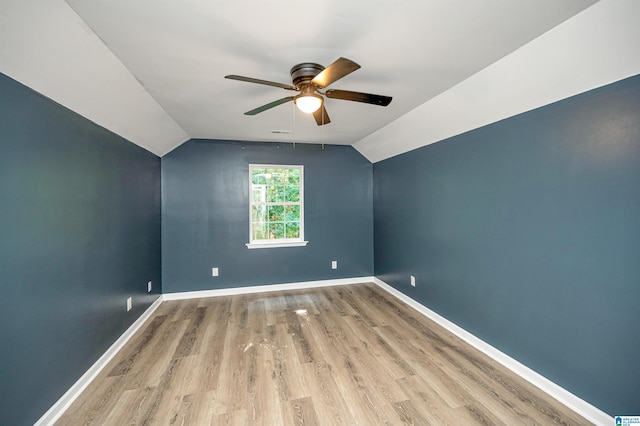 spare room featuring vaulted ceiling, wood finished floors, a ceiling fan, and baseboards