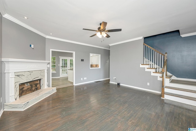 unfurnished living room featuring baseboards, ceiling fan, a premium fireplace, wood finished floors, and stairs