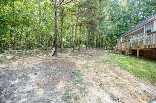 view of yard with a forest view and a wooden deck