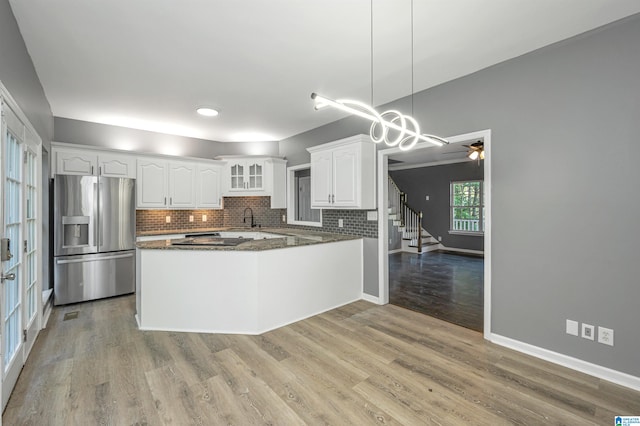 kitchen featuring light wood-type flooring, ceiling fan with notable chandelier, stainless steel fridge, kitchen peninsula, and white cabinets