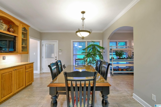 dining space with ornamental molding, arched walkways, and baseboards