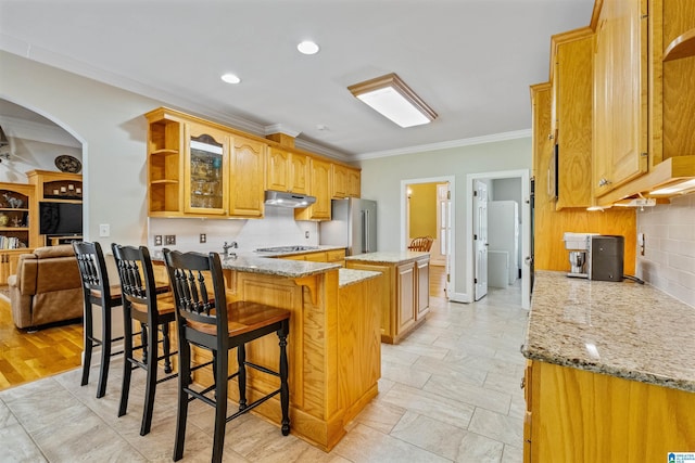 kitchen featuring under cabinet range hood, stainless steel appliances, a peninsula, open shelves, and crown molding