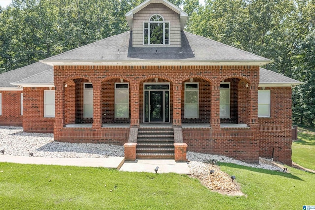 view of front of property featuring covered porch, a shingled roof, and brick siding