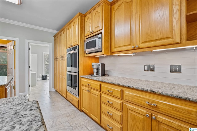 kitchen featuring double oven, light stone counters, built in microwave, ornamental molding, and decorative backsplash