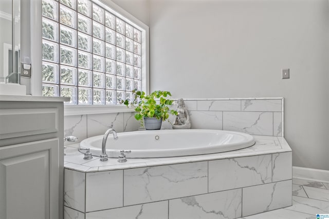 bathroom featuring marble finish floor, baseboards, a garden tub, and vanity