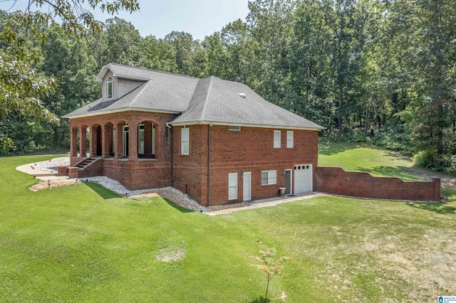 view of side of home with a yard, brick siding, an attached garage, and driveway