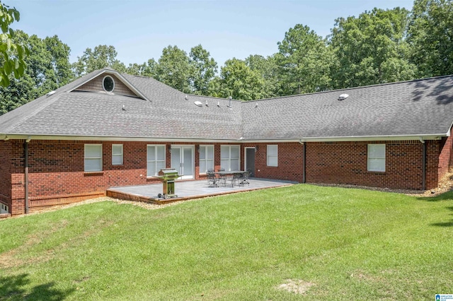 back of property featuring a yard, a shingled roof, a patio area, and brick siding