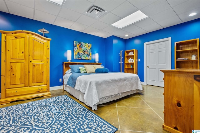 bedroom with baseboards, visible vents, a drop ceiling, and tile patterned floors