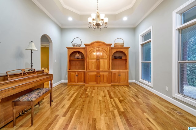 living area with a raised ceiling, baseboards, visible vents, and light wood finished floors