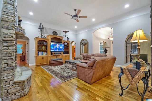 living room featuring light wood finished floors, baseboards, arched walkways, and a ceiling fan