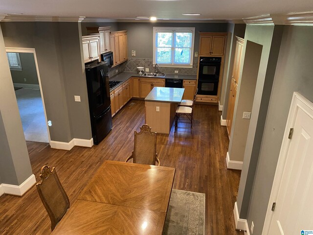 kitchen featuring tasteful backsplash, dark wood finished floors, a kitchen breakfast bar, black appliances, and a sink