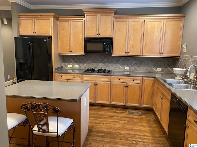 kitchen featuring wood finished floors, a sink, backsplash, black appliances, and crown molding