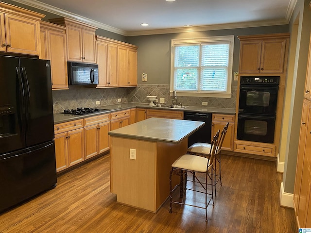 kitchen with a breakfast bar, a sink, ornamental molding, dark wood-style floors, and black appliances