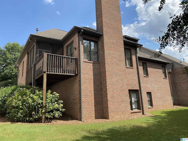 view of side of property featuring a balcony, a yard, a chimney, and brick siding