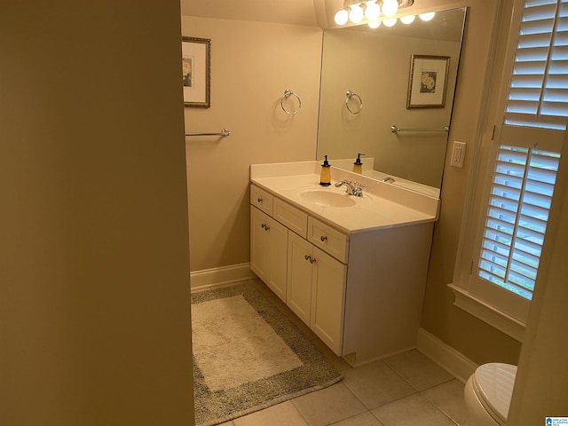 half bath with toilet, tile patterned flooring, vanity, and baseboards