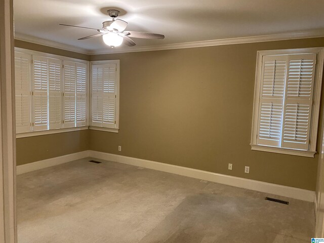 spare room featuring ceiling fan, ornamental molding, visible vents, and baseboards