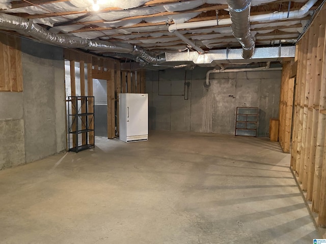 unfinished basement featuring freestanding refrigerator