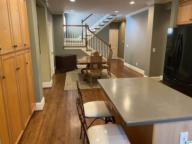 kitchen with crown molding, dark wood-type flooring, and black fridge