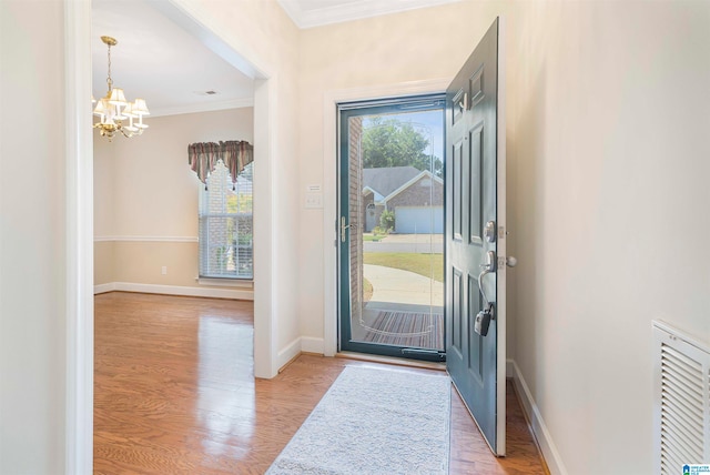 doorway to outside with light wood-type flooring, ornamental molding, and a chandelier