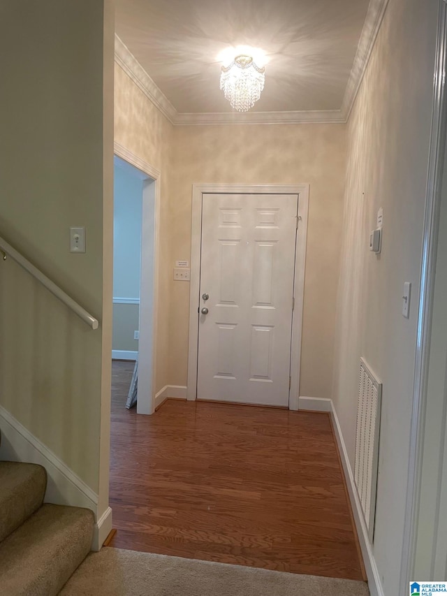 entrance foyer with crown molding, hardwood / wood-style flooring, and a notable chandelier